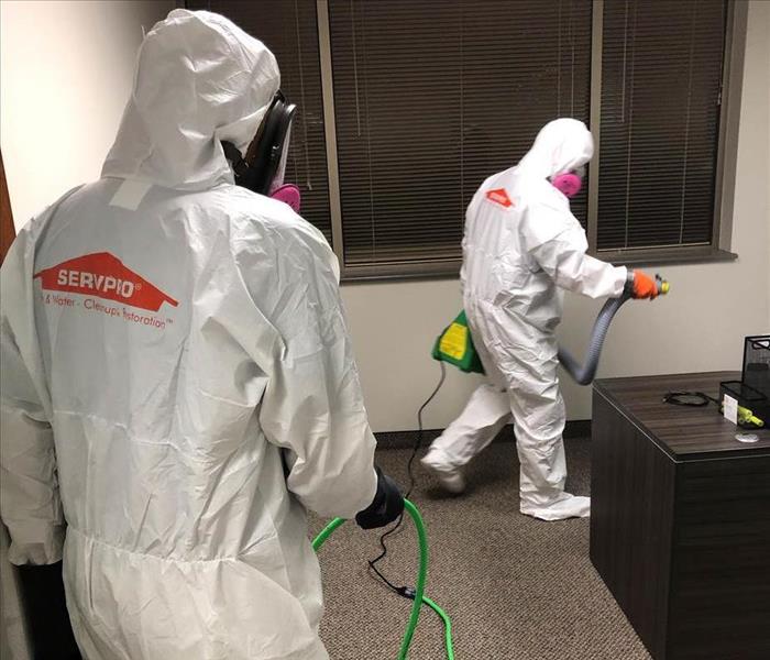SERVPRO employees dressed in full PPE and sanitizing a place of business in Raleigh with fogging techniques
