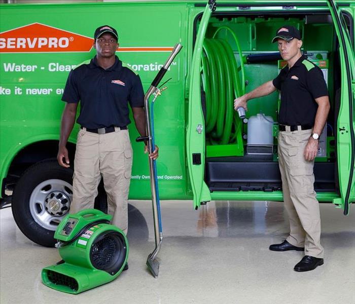 Two SERVPRO team members posing for a photo in front of van.